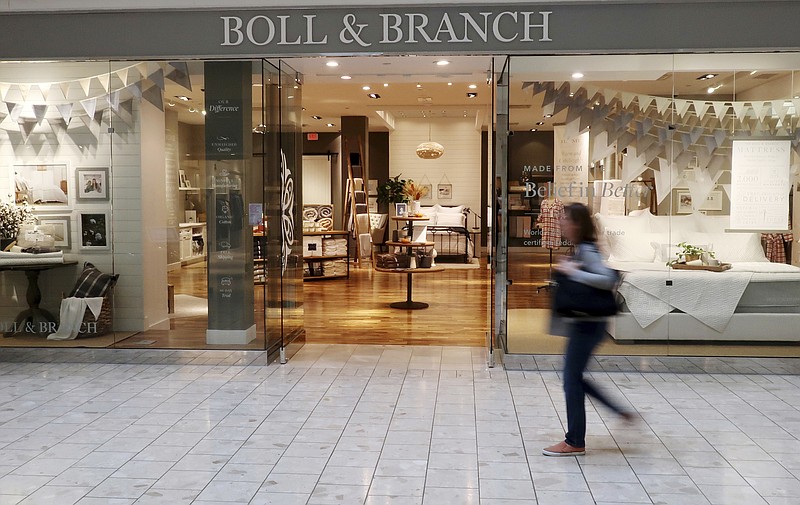 In this Nov. 2, 2018 photo, a patron at the Mall at Short Hills in Short Hills, N.J., passes the Boll & Branch furniture store. At the upscale mall such digital natives as Untuckit, Casper, Boll & Branch and Indochino are becoming destinations for shoppers and are helping to drive more sales and traffic, says Jamie Cox, mall manager. The online retailers are an integral part of the mall’s overall strategy to recruit retailers that offer special shopping experiences. (AP Photo/Ted Shaffrey)