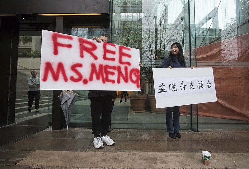 Supporters hold signs outside the British Columbia Supreme Court in Vancouver during the third day of a bail hearing for Meng Wanzhou, the chief financial officer of Huawei Technologies, on Tuesday December 11, 2018. (Darryl Dyck/The Canadian Press via AP)