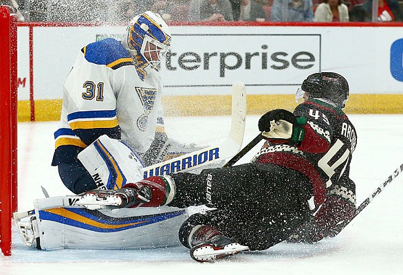 Josh Archibald of the Coyotes crashes into Blues goaltender Chad Johnson as Johnson makes a save during a game earlier this month in Glendale, Ariz.