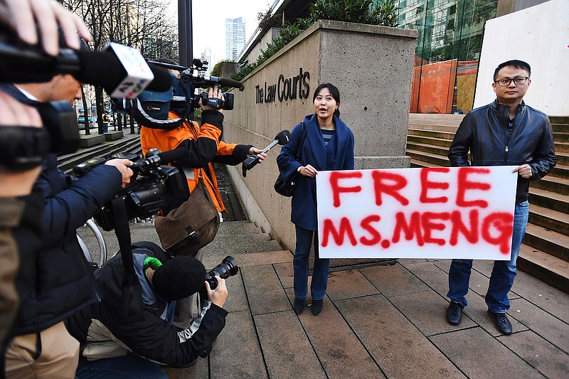 People hold a sign Monday at a Vancouver, British Columbia, courthouse prior to the bail hearing for Meng Wanzhou, Huawei's chief financial officer. Meng was detained at the request of the U.S. during a layover Dec. 1 at the Vancouver airport.
