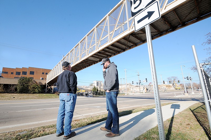 Capital Paving and Construction project manager Drew Leary talks on the phone Monday as he and Kenly Jones work out a plan to remove the pedestrian bridge over Missouri Boulevard at the old St. Mary's hospital site. Missouri Boulevard will be closed in the area starting Monday, but will be complete in time for Tuesday morning's commute.