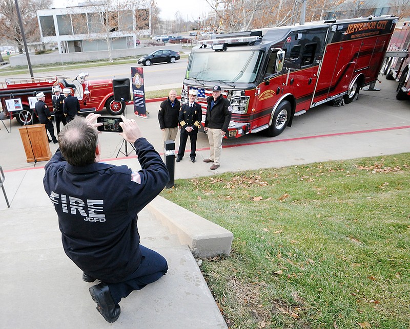 Fire Capt. Scott Spencer takes a photo of his mates posing with the Jefferson City Fire Department's new equipment Tuesday at the Miller Performing Arts Center parking lot. The fleet includes seven new fire vehicles.