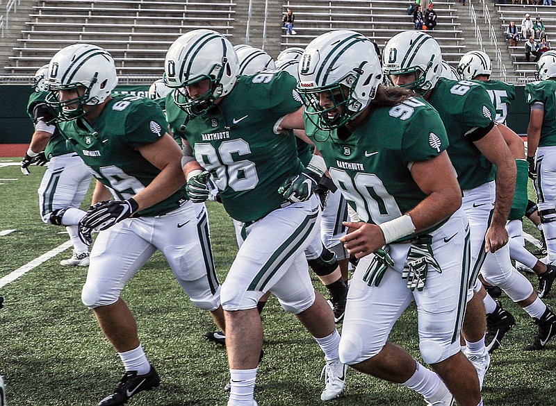 In this Sept. 29, 2018, photo provided by Dartmouth College, Seth Simmer (96) is flanked by Tommy Ciesla (69) and Niko Lalos (90) during warmups before an NCAA college football game between Dartmouth and Penn in Hanover, N.H. During his freshman season at Dartmouth, Seth Simmer was having trouble hearing the linebackers call signals from his defensive tackle spot just a few yards away. What was first diagnosed as an ear infection brought on by a severe head cold turned out to be a brain tumor that was making him deaf in his left ear. Simmer is one of 30 nominees for the Mayo Clinic Comeback Player of the Year Award. (Tom McNeill/Dartmouth College via AP)