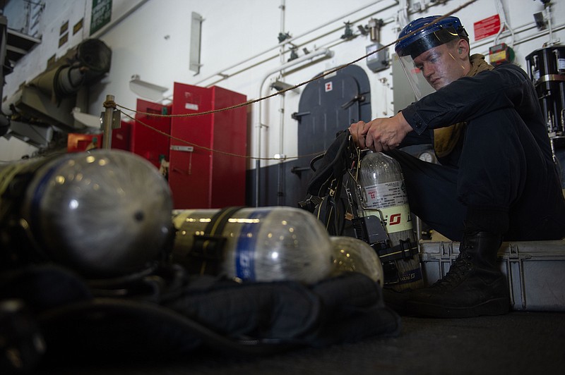 U.S. Navy Damage Controlman 3rd Class Jacob Mauk, from Texarkana, Ark., refills self-contained breathing apparatus canisters Wednesday in the hangar bay aboard the aircraft carrier USS John C. Stennis (CVN 74) in the Arabian Sea. The John C. Stennis Carrier Strike Group and the Essex Amphibious Ready Group are conducting integrated operations in the Arabian Sea to ensure stability and security in the Central Region, connecting the Mediterranean and the Pacific through the western Indian Ocean and three strategic choke points, according to a Navy news release. (U.S. Navy photo by Mass Communication Specialist Mitchell Banks)
