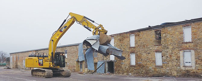 A heavy piece of machinery cleans up old aluminum roofing materials before tearing down the old structure.