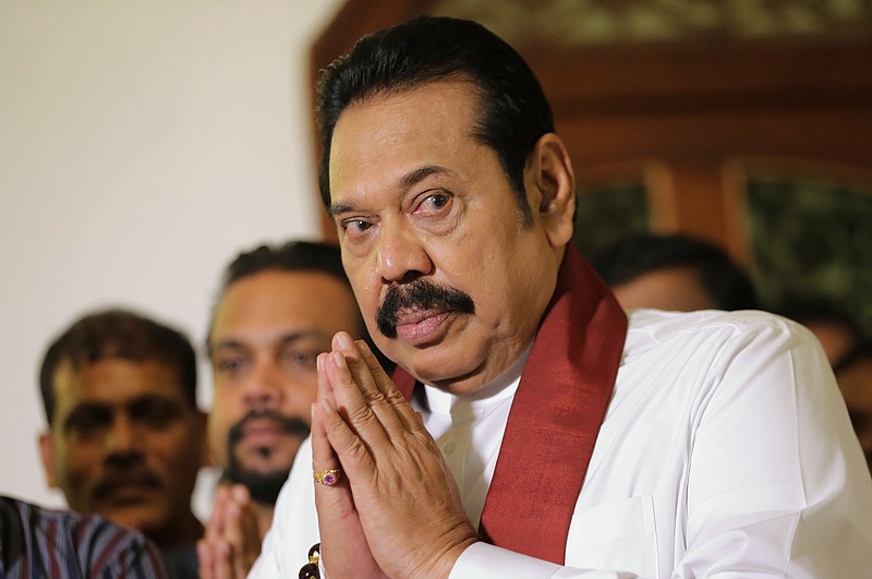 Sri Lanka's disputed prime minister Mahinda Rajapaksa folds his hands in prayer as he is blessed by a Buddhist monk after signing his resignation paper in Colombo, Sri Lanka, Saturday, Dec. 15, 2018. Rajapaksa resigned on Saturday, saying he wants to end a political impasse over his appointment. (AP Photo/Eranga Jayawardena)