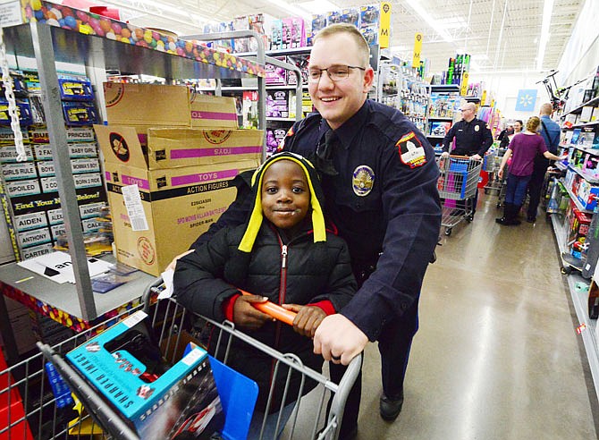 Patrol Officer Ryan Seymour and Dajhaun Berth-Robertson, 6, shop for Christmas gifts Saturday while on a holiday spending spree during Operation TOYS (Take Our Youth Shopping) at Walmart Supercenter. Hundreds of cops and children teamed up for the outing.