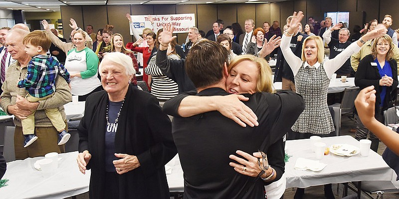 In this Nov. 8, 2018 photo at Missouri Farm Bureau Headquarters in Jefferson City, attendees sway and wave their arms to the song "We are the Champions" as United Way of Central Missouri Campaign co-chair Ryan Freeman receives a congratulatory hug from Claudia Kehoe following the announcement that the annual campaign goal was surpassed by more than 18 percent for a projected total of $2.187,521. Standing at left is former UW CEMO President Linda McAnany. 
