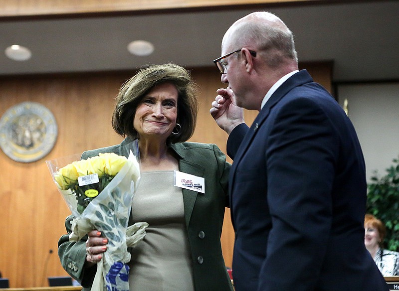 Texarkana, Ark., Mayor Ruth Penney-Bell hugs Texarkana, Texas, Mayor Bob Bruggeman after he presented her with a bouquet of yellow roses Monday at Penney-Bell's last city board meeting. Penney-Bell served one term as the Arkansas-side's first female chief executive.