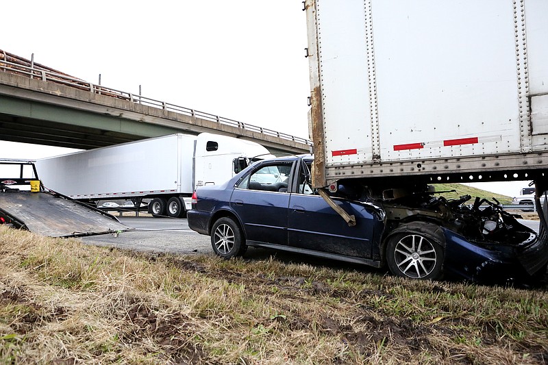 A blue Honda Accord remains pinned underneath an 18-wheeler trailer on the side of Interstate 30 westbound on Tuesday, December 18, 2018, in Mandeville, Ark. Construction along Interstate 30 made traffic slow down and the car crashed into the back of the 18-wheeler. The driver of the 18-wheeler thought it was another truck that hit the trailer from behind, but ended up dragging the car several yards where the crash actually happened. The driver of the Honda Accord was transported to Christus St. Michael's Hospital.