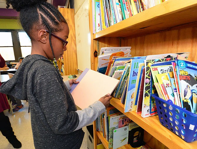 In this Dec. 18, 2018 photo, Heaven Guthrie looks through books at the Jefferson City Boys & Girls Club. Her mom, LaDonna, works at the club.