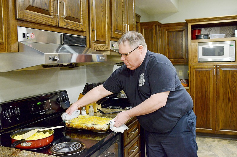 Firefighter Kevin Bagby removes a fresh casserole from the oven as he helps prepares a Christmas Day breakfast Tuesday at the Jefferson City Fire Department Station 3.