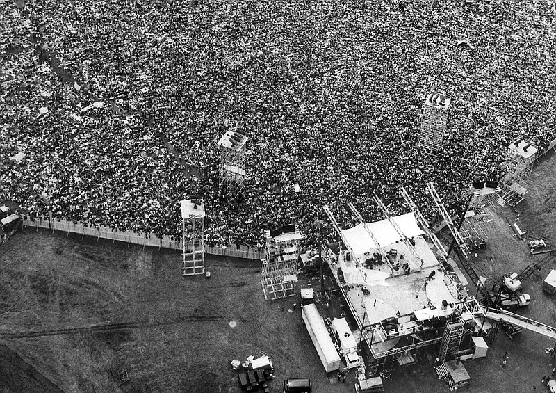 FILE - In this Aug. 16, 1969 file aerial photo, music fans pack around the stage at the original Woodstock Music and Arts Festival, lower right, in Bethel, N.Y. The Bethel Woods Center for the Arts, a concert venue built on the original Woodstock site, announced Thursday, Dec. 27, 2018, that it will host the 50th anniversary of the historic event at the original Woodstock concert site on Aug. 16-18, 2019. (AP Photo/Marty Lederhandler, File)