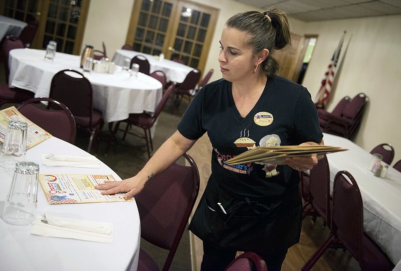 In this Tuesday, Dec. 18, 2018 photo, Shawna Green, waitress at Granny Shaffer's, puts out menus for customers at the restaurant in Joplin, Mo. Wages will be increasing for millions of low-income workers across the U.S. as the new year ushers in new laws in numerous states. In Missouri and Arkansas, minimum wages are rising as a result of voter-approved ballot initiatives.  (Roger Nomer/The Joplin Globe via AP)