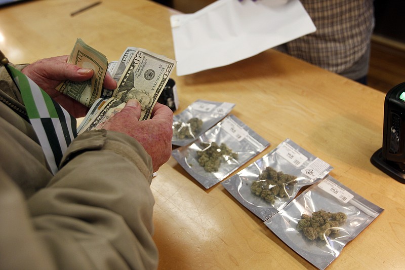 In this Monday, Jan. 1, 2018 file photo, a customer purchases marijuana at the Harborside marijuana dispensary in Oakland, Calif., on the first day that recreational marijuana was sold legally in California. 
