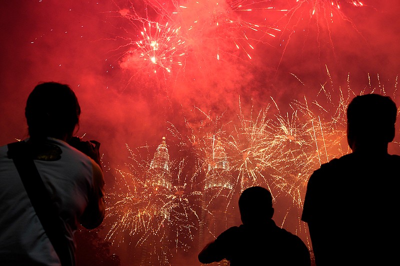 Spectators watch as fireworks explode in front of Malaysia's landmark building, the Petronas Twin Towers, during the New Year's celebration in Kuala Lumpur, Malaysia, Tuesday, Jan. 1, 2019.(AP Photo/Yam G-Jun)