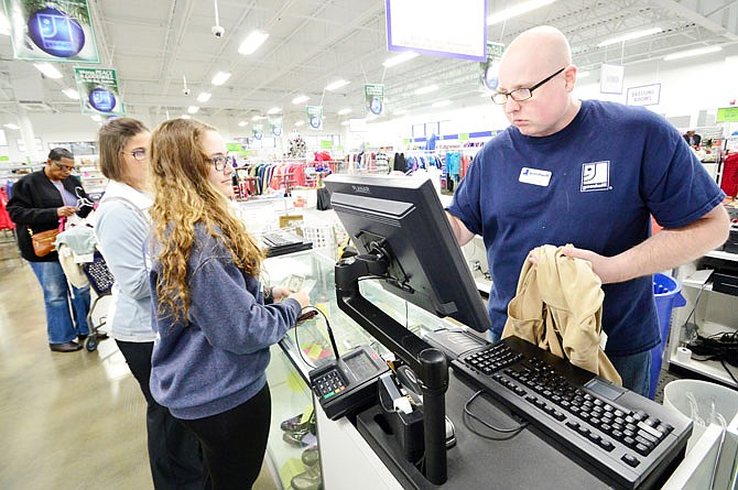 Joshua Turner, of Goodwill, checks out customers Wednesday at the store located at 2821 S. Ten Mile Drive. Goodwill merged with the MORE Group.