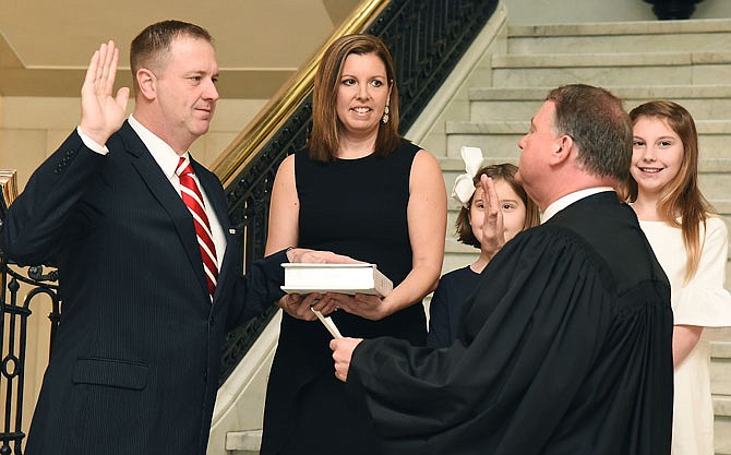 Eric Schmitt holds up his right hand and repeats the oath of office Thursday while being sworn in as Missouri's 43rd attorney general during a brief ceremony at the Missouri Supreme Court. Chief Justice Zel Fischer, foreground right, swore in Schmitt to replace Josh Hawley who resigned to serve on the United States Senate. Standing with Schmitt is his wife, Jaime, and their daughters Olivia, 8, and Sophia, 10.