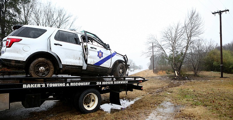 Cpl. Clayton McWilliams' Arkansas state trooper vehicle sits on the back of a tow truck after hydroplaning and striking a tree on the side of U.S. Highway 71 on Thursday near Wilton, Ark. McWilliams was taken to a local hospital before being transported to Little Rock.