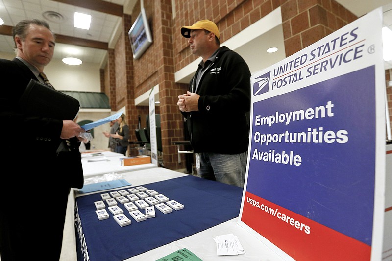FILE- In this Nov. 2, 2017, file photo a recruiter from the postal service, right, speaks with an attendee of a job fair in the cafeteria of Deer Lakes High School in Cheswick, Pa.  Even with fear of a global economic slump depressing stock markets, Friday, Jan. 4, 2019 jobs report for December is expected to offer reassurance that the U.S. economy remains sturdy and on track to expand for a 10th straight year.  (AP Photo/Keith Srakocic, File)
