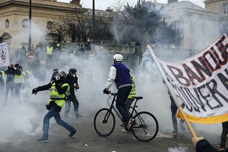 Demonstrators stand in tear gas thrown by riot police during a protest in Paris, Saturday, Jan. 5, 2019. Hundreds of protesters were trying to breathe new life into France's apparently waning yellow vest movement with marches in Paris and gatherings in other cities. (AP Photo/Kamil Zihnioglu)