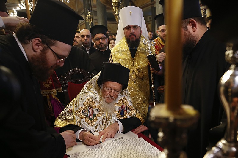 Ecumenical Patriarch Bartholomew I, center, signs the "Tomos" decree of autocephaly for the Ukrainian church as Metropolitan Epiphanius, center right, the head of the independent Ukrainian Orthodox Church looks on during the ceremony at the Patriarchal Church of St. George in Istanbul, Saturday, Jan. 5, 2019. The Ecumenical Patriarch of Constantinople has signed a decree of independence for the Orthodox Church of Ukraine. (AP Photo/Emrah Gurel)