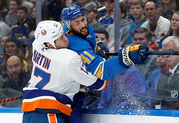 Robert Bortuzzo of the Blues is checked into the boards by Matt Martin of the Islanders during Saturday night's game in St. Louis.