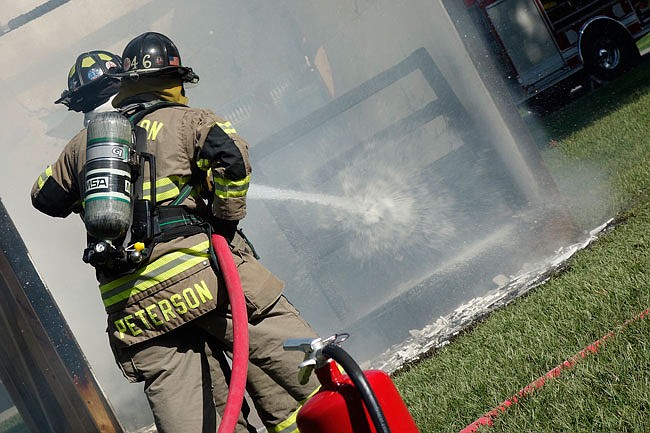 Enveloped by steam, Fulton firefighter Scott Peterson and his rookie for the day, WWU student Megan Tolias, edge closer to their target. A controlled fire of a fake dorm room was conducted on Sept. 12. 