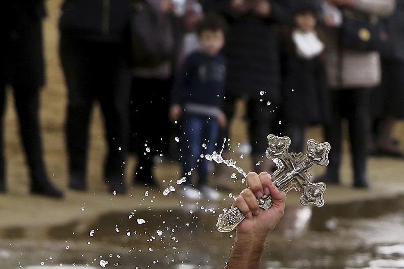 A swimmer holds up the cross after it was thrown from an Orthodox priest into the water, during an epiphany ceremony to bless the sea at Famagousta or Varosia beach in the Turkish Cypriots breakaway north part of the eastern Mediterranean divided island of Cyprus, Sunday, Jan 6, 2019. Many Orthodox Christian faithful attended the Epiphany Day blessing of the waters in Famagusta in Cyprus', the fourth time the ceremony has taken place since 1974 when the small island nation was cleaved along ethnic lines. (AP Photo/Petros Karadjias)