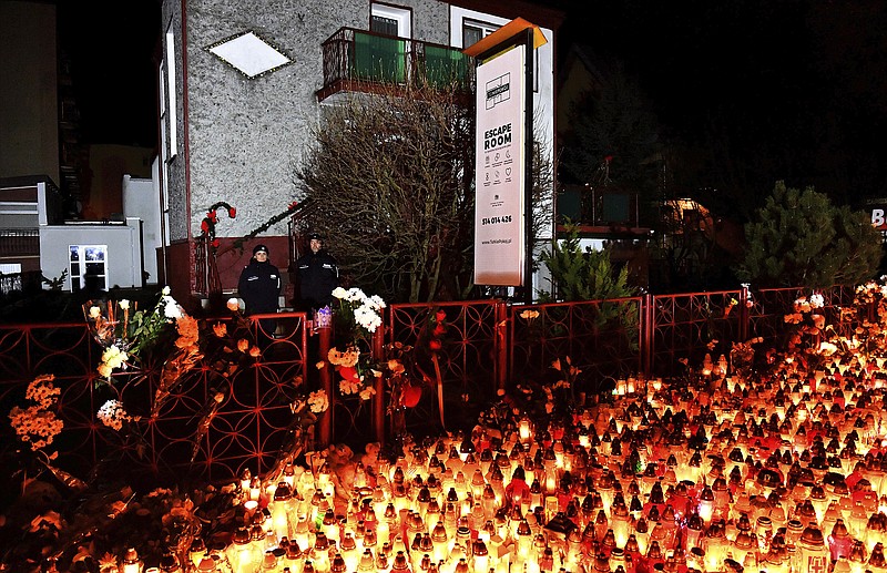 Lights, flowers and toys are left outside the escape room entertainment site where five teenage girls died in a fire last week, in Koszalin, northern Poland, on Sunday, Jan. 6, 2019.  Sunday was designated a day of mourning and prayers in Koszalin for the girls and their families. (AP Photo)