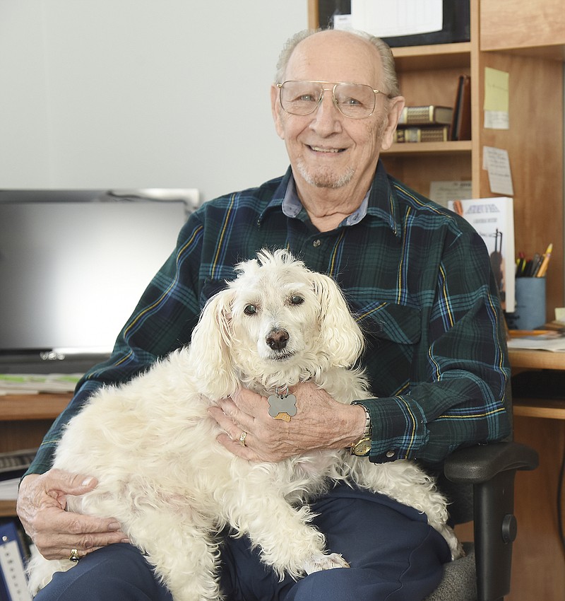 Tom Ault poses with his 12-year-old schnoodle, Jake, on Friday at his westside Jefferson City home. Ault has written numerous book, a great number of them about his canine companion. 