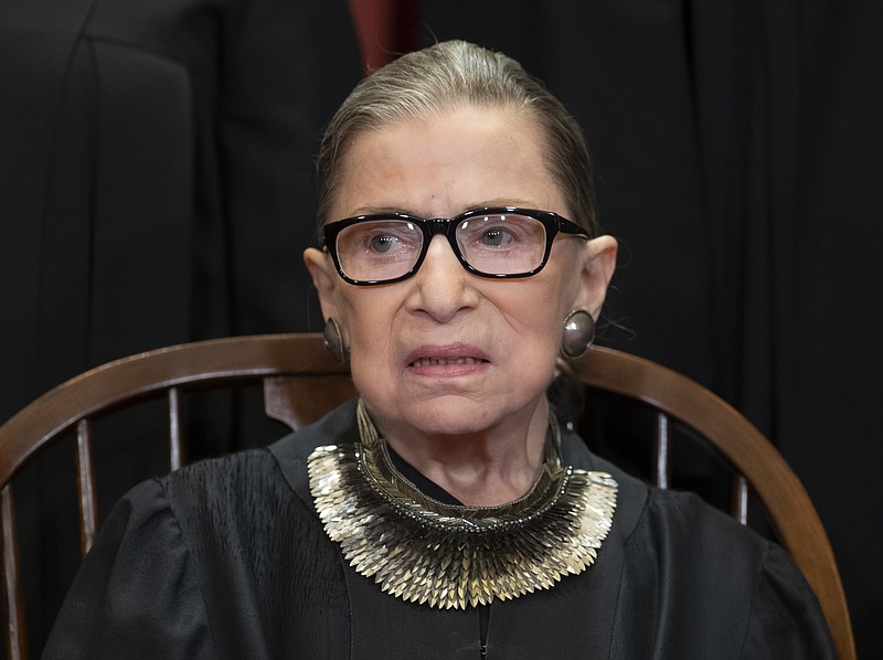 FILE - In this Nov. 30, 2018 file photo, Associate Justice Ruth Bader Ginsburg, nominated by President Bill Clinton, sits with fellow Supreme Court justices for a group portrait at the Supreme Court Building in Washington.  The Supreme Court says Ginsburg is missing arguments for the first time in more than 25 years as she recuperates from cancer surgery last month. (AP Photo/J. Scott Applewhite)