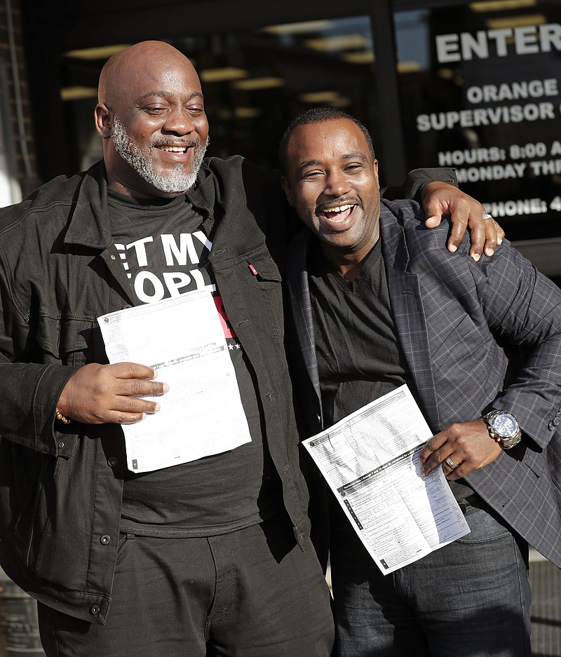 Former felons Desmond Meade, president of the Florida Rights Restoration Coalition, left, and David Ayala, husband of State Attorney Aramis Ayala, celebrate with copies of their voter registration forms after they registered at the Supervisor of Elections office Tuesday, Jan. 8, 2019, in Orlando, Fla. Former felons in Florida began registering for elections on Tuesday, when an amendment that restores their voting rights went into effect. (AP Photo/John Raoux)