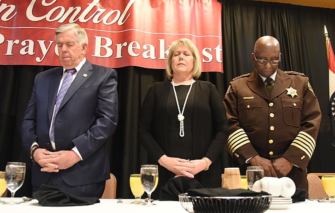 Gov. Mike Parson, left, first lady Teresa Parson and St. Louis City Sheriff Vernon Betts bow their heads Thursday during the invocation by Pastor Billy Russell of the First Baptist Church of Bolivar at the annual Governor's Prayer Breakfast at Capitol Plaza Hotel. Betts was the featured speaker.