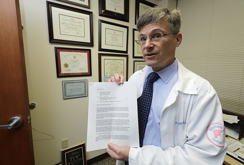 In this Dec. 20, 2018, photo, Dr. Jeffrey Clemons, a pelvic reconstructive surgeon, poses for a photo in Tacoma, Wash., with a letter to state Attorney General Bob Ferguson that he helped draft and was signed by more than 60 Washington state surgeons. The letter argues that Ferguson's consumer-protection lawsuit against Johnson & Johnson and its Ethicon Inc. subsidiary over products used to treat pelvic floor disorders and incontinence in women might scare patients away from the best treatment options. (AP Photo/Ted S. Warren)