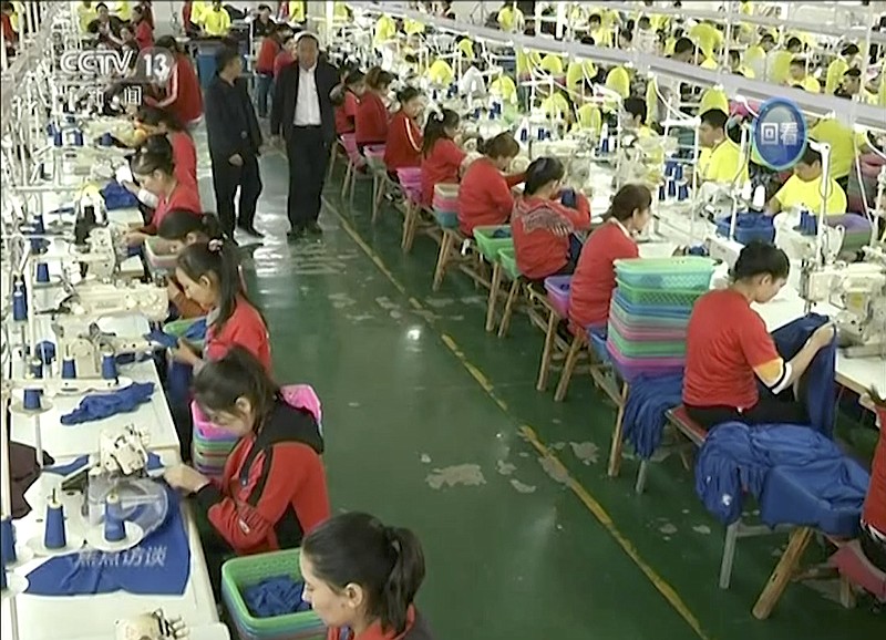 FILE - In this file image from undated video footage run by China's CCTV via AP Video, Muslim trainees work in a garment factory at the Hotan Vocational Education and Training Center in Hotan, Xinjiang, northwest China. A U.S. company that stocks college bookstores with t-shirts and other team apparel cut ties Wednesday, Jan. 9, 2019, with a Chinese company that drew workers from an internment camp holding targeted members of ethnic minority groups. (CCTV via AP Video, File)