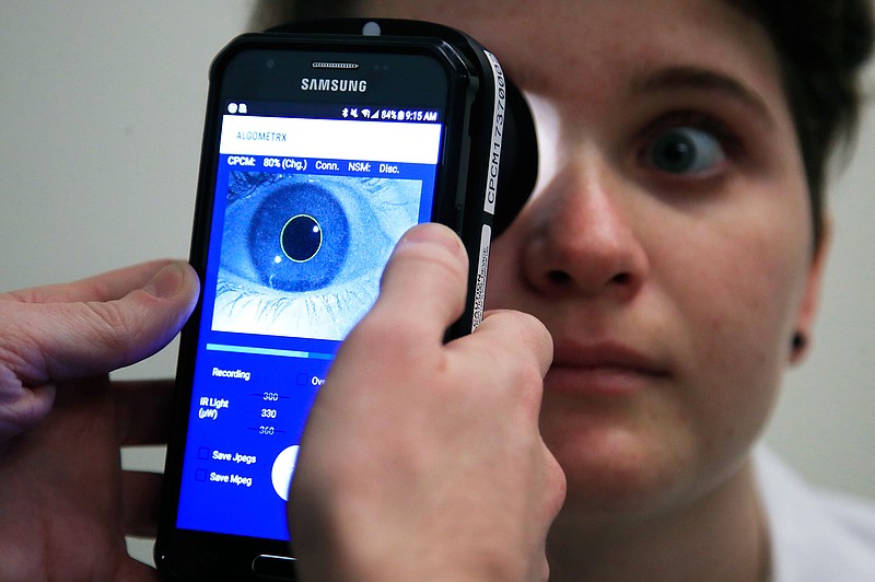 Clinical Research Assistant Kevin Jackson uses AlgometRx Platform Technology on Sarah Taylor's eyes to measure her degree of pain at the Children's National Medical Center in Washington, Monday, Dec. 10, 2018. Children's National Medical Center is testing an experimental device that aims to measure pain according to how pupils react to certain stimuli. (AP Photo/Manuel Balce Ceneta)