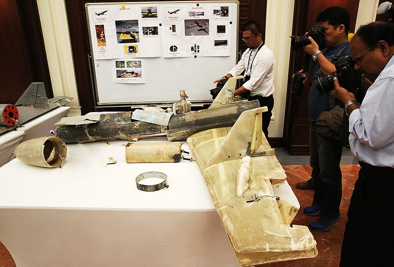In this June 19, 2018 file photo, photographers take pictures of what U.A.E. officials described as an Iranian Qasef drone captured on the battlefield in Yemen during a news conference in Abu Dhabi, United Arab Emirates. A deadly bomb-laden drone flown by Yemen's Houthi rebels flew into a military parade on Thursday, Jan. 10, 2019, outside of the southern port city of Aden, targeting high-ranking military officials in Yemen's internationally recognized government. The brazen attack threatens U.N.-brokered peace efforts to end the yearslong war tearing at the Arab world's poorest nation. (AP Photo/Jon Gambrell, File)