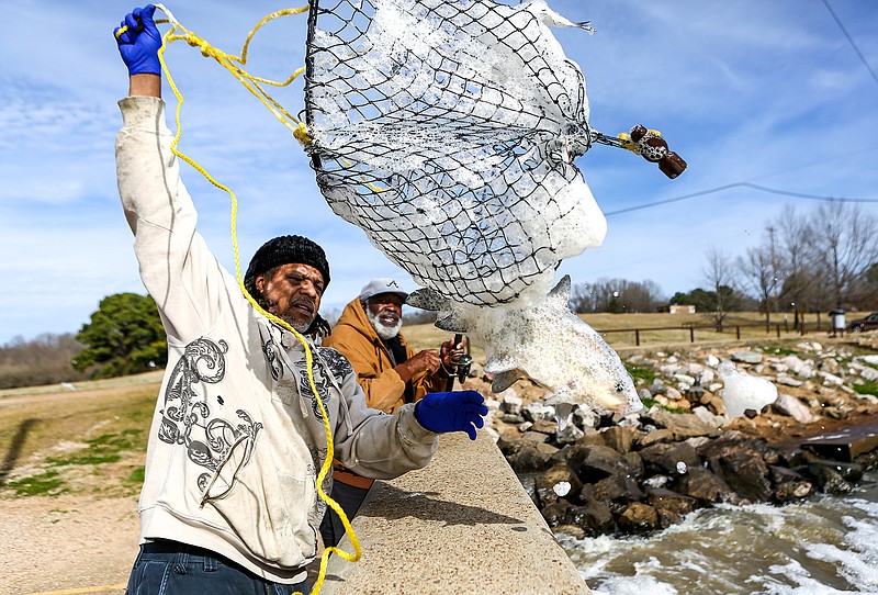 Darell Stone yanks the fishing net over the wall from the water with Earl West's buffalo fish in it on Thursday at the Wright Patman Lake spillway south of Texarkana, Texas.
