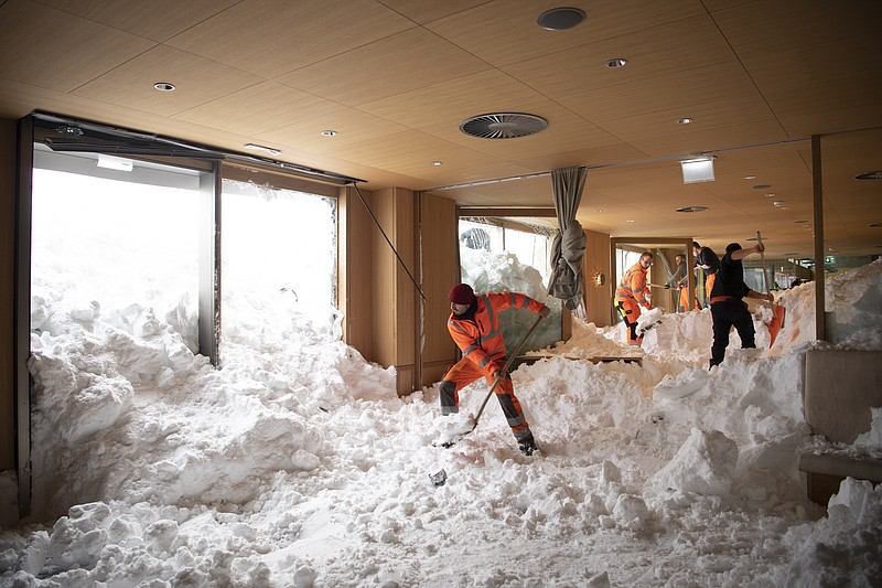 People clear snow from inside the Hotel Saentis in Schwaegalp, Switzerland,, Switzerland, Friday Jan. 11, 2019, after an avalanche. Police said three people were slightly hurt when the avalanche hit the hotel at Schwaegalp on Thursday afternoon. (Gian Ehrenzeller/Keystone via AP)