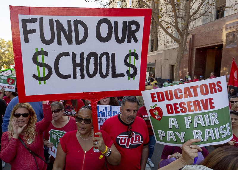 FILE - In this Dec. 15, 2018, file photo, thousands of teachers marched and rallied in downtown Los Angeles.  Strike or no strike, after a deal is ultimately reached on a contract for Los Angeles teachers, the school district will still be on a collision course with deficit spending because of pensions and other financial obligations. .(AP Photo/Damian Dovarganes, File)