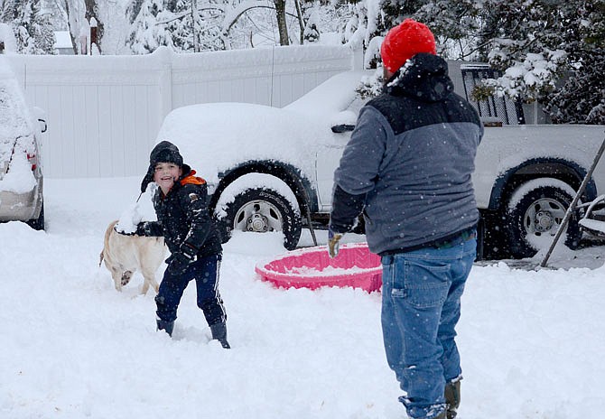 Brody Williams, 6, has a snowball fight with his dad, Chris Willliams, and their dog, Graham, on Saturday in the family's backyard. 
