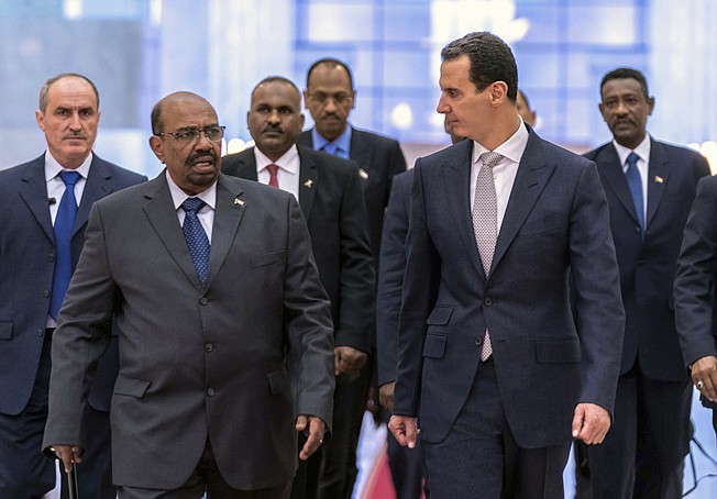 Syrian President Bashar Assad, right, meets with Sudan's President Omar Bashir on Dec. 16, 2018, in Damascus, Syria.  Assad has survived years of war and millions of dollars in money and weapons aimed at toppling him. Now after nearly eight years of conflict, he is poised to be readmitted to the fold of Arab nations, a feat once deemed unthinkable as he brutally crushed a years-long uprising against his family's rule. Key border crossings with neighbors, shuttered for years by the war, have reopened, and Arab commercial airlines are reportedly considering resuming flights to Damascus.
