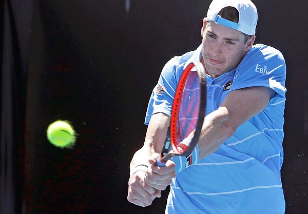 John Isner makes a backhand return to Reilly Opelka during Monday's first-round match at the Australian Open in Melbourne, Australia