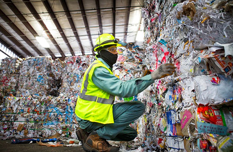 A Waste Management employee removes plastic that made it through the sorting process from a bale of mixed paper that is being prepared to be loaded onto a truck on Nov. 19, 2018, at the company's facility on Gasmer Drive in southwest Houston. 