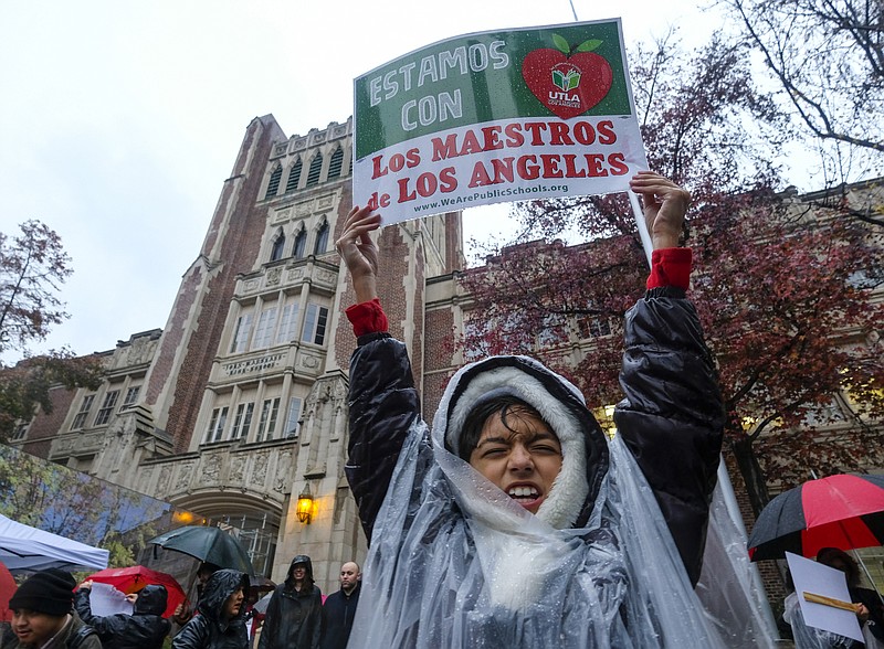 Alessandro Niculescu, 10, holds up a sign in the rain during a teacher strike outside John Marshall High School, Monday, Jan. 14, 2019, in Los Angeles. Tens of thousands of Los Angeles teachers are striking after contentious contract negotiations failed in the nation's second-largest school district.(AP Photo/Ringo H.W. Chiu)