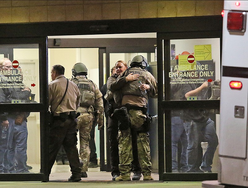 Ector County Sheriff deputies hug in the ambulance entrance at Medical Center Hospital after three sheriff's deputies were shot in the line of duty, according to the Odessa American, late Monday, Jan. 14, 2019, in North Odessa, Texas. (Jacob Ford/Odessa American via AP)