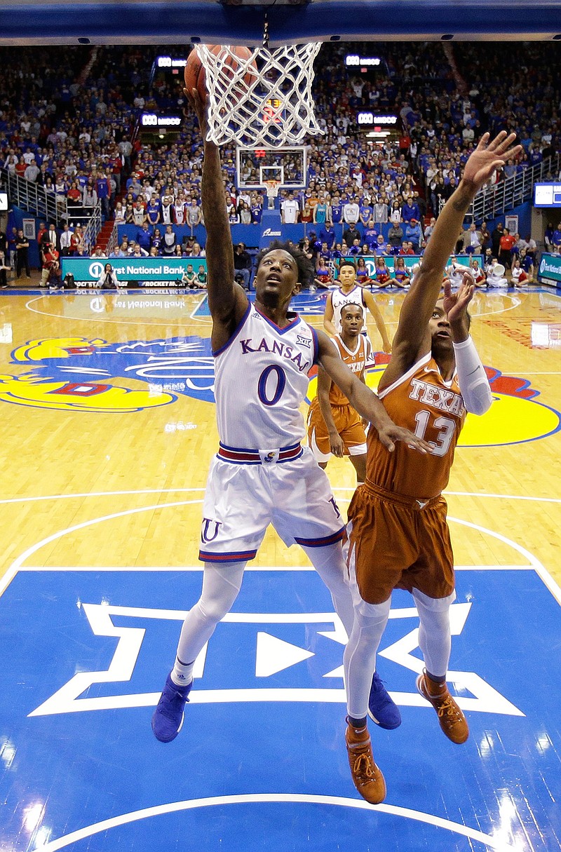 Kansas guard Marcus Garrett (0) gets past Texas guard Jase Febres (13) to put up a shot during the first half of an NCAA college basketball game Monday, Jan. 14, 2019, in Lawrence, Kan. (AP Photo/Charlie Riedel)