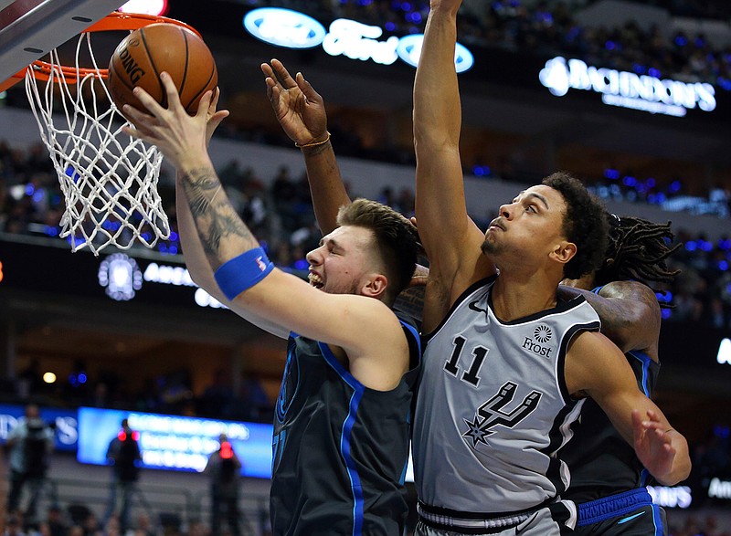 Dallas Mavericks forward Luka Doncic (77) pulls down a rebound against San Antonio Spurs guard Bryn Forbes (11) in the first half of an NBA basketball game, Wednesday, Jan. 16, 2019, in Dallas. (AP Photo/Richard W. Rodriguez)