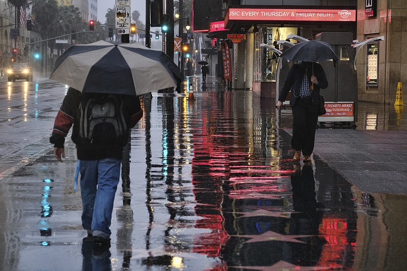 Pedestrians make their way along a rain soaked Hollywood Blvd. in Los Angeles on Thursday, Jan. 17, 2019. The latest in a series of Pacific Ocean storms pounded California with rain and snow Thursday, prompting officials to put communities on alert for mudslides and flooding and making travel treacherous. (AP Photo/Richard Vogel)